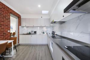 a kitchen with white cabinets and a brick wall at 205 Modern King BR with Fast WiFi - Brunswick East in Melbourne +14 photos