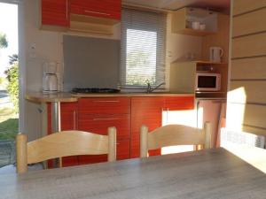 a kitchen with wooden cabinets and a table and chairs at Mobil Home Confortable avec Terrasse - API-1-52-390 in Saint-Sornin