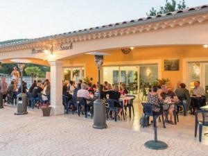 a group of people sitting at tables outside of a restaurant at Mobil home 6 pers avec terrasse - API-1-52-222 in Saint-Maurice-dʼIbie