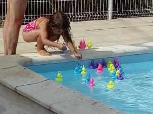 a little girl playing with toy ducks in a swimming pool at Mobil Home 32m² 4 pers, Terrasse à St-Sornin - API-1-52-727 in Saint-Sornin