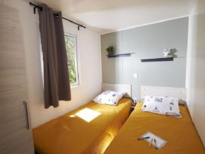 two beds in a small room with a window at Mobil-home avec Terrasse pour 6 Personnes en Ardèche - API-1-52-360 in Saint-Maurice-dʼIbie +25 photos