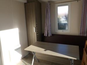 una mesa de madera en una habitación con ventana en Mobil home avec terrasse - 2 personnes - API-1-52-276, en Saint-Sornin 19 fotos más