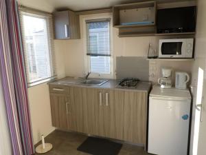 a small kitchen with a sink and a refrigerator at Mobil-home cosy avec terrasse pour 2 personnes - API-1-52-276 in Saint-Sornin