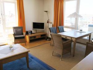 a living room with a table and chairs and a television at Kaiserhof 302 in Wangerooge