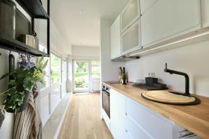 a kitchen with white cabinets and a wooden counter top at Lighthousestudio & Spa- Exclusive Entspannt Besonders in Wangerooge