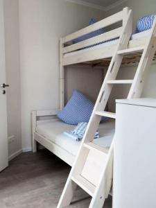万根沃格Bootshaus Achterstag的客房内的白色双层床,带梯子