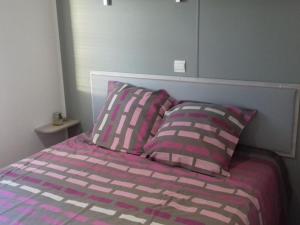a bed with pink and purple sheets and two pillows at Mobil-home 33m² avec terrasse au Boulou - API-1-52-398 in Le Boulou