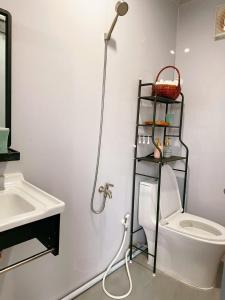 a bathroom with a toilet and a shelf next to a sink at An Nhiên Homestay Phước Hải in Chợ Phước Hải