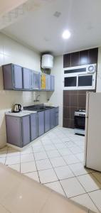 a kitchen with blue cabinets and a white tile floor at المبيت 4 للشقق المخدومه in Abha