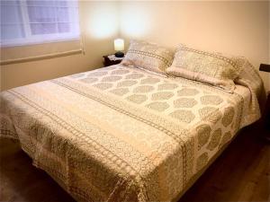 a bedroom with a bed with a white bedspread and a window at Alojamiento in Calbuco