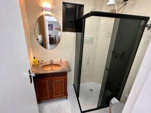 Un baño con lavabo y ducha con espejo. en Apê na Enseada - Ar, Wi-Fi, garagem e praia a pé!, en Guarujá 9 fotos más