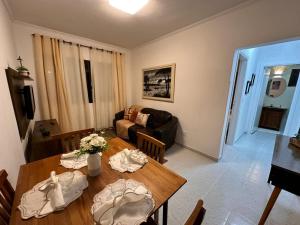 una sala de estar con una mesa y un sofá en Apê na Enseada - Ar, Wi-Fi, garagem e praia a pé!, en Guarujá