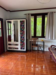 a living room with a tiled floor and windows at Room with a view Chaloklum in Koh Phangan