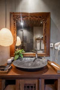 a bathroom with a large stone sink in front of a mirror at Joglo Retreat in Canggu