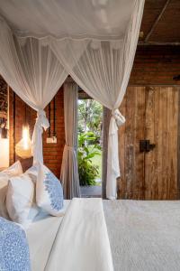 a bedroom with a bed with a canopy and a window at Joglo Retreat in Canggu