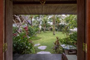 an open door to a garden from a house at Joglo Retreat in Canggu