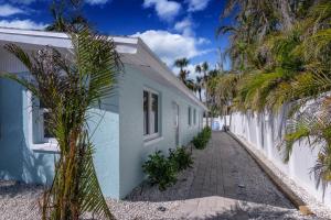 a white building with palm trees next to a sidewalk at Restorative Escape-Moonlit Waters-Steps to beach. in Holmes Beach
