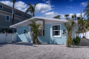 a blue house with palm trees in front of it at Tranquility Meets Style-Walk to beach-prvt pool. in Holmes Beach