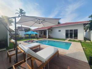 una casa con piscina y una sombrilla blanca en Jasibe Oceanside in Amatecampo - Steps to beach - Flexible Checkout, en El Porvenir