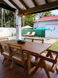 Una mesa de comedor de madera con sillas y una sombrilla. en Jasibe Oceanside in Amatecampo - Steps to beach - Flexible Checkout, en El Porvenir