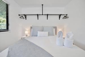 a white bedroom with a large bed with white pillows at Cozy Cottage at Sunshine Grove in Peachester