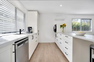 a kitchen with white cabinets and a sink and a window at Cozy Cottage at Sunshine Grove in Peachester +16 photos