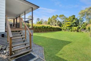 a porch of a house with a lawn at Cozy Cottage at Sunshine Grove in Peachester