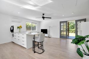 a white kitchen with a desk and a ceiling fan at Cozy Cottage at Sunshine Grove in Peachester
