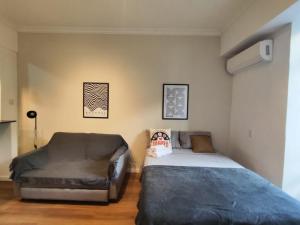 a bedroom with a bed and a couch at Studio SDU Aeroporto VLT Metrô Cinelândia in Rio de Janeiro