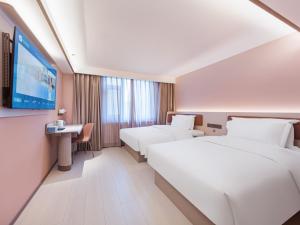 a hotel room with two beds and a flat screen tv at Hanting Hotel Beijing Fangzhuang Fangxingyuan in Beijing