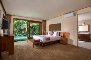 a bedroom with a bed and a television in a room at Senetan Villas and Spa Resort in Payangan