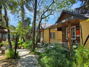 une petite maison jaune avec un porche et des arbres dans l'établissement MangoBungalow, à Hue