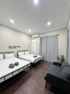 a room with two beds and a couch in it at Tolomhouse in Hat Yai