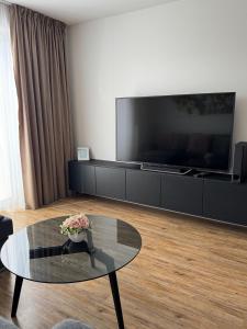 Una sala de estar con una mesa de cristal y un televisor grande. en Apartment Tatry in the center of Poprad with view, en Poprad