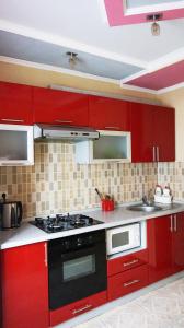 a kitchen with red cabinets and a stove top oven at Apartments Tiraspol in Tiraspol