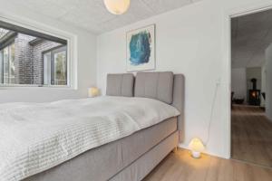 a white bedroom with a large bed and a window at Holiday Home In 1St Row By The Limfjord in Thyholm