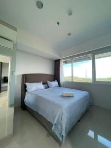 a bedroom with a large bed with two windows at The Nove Apartment Kalani Tower Sea View in Pulau Nongsa