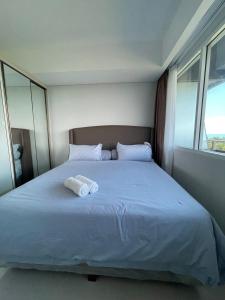 a bedroom with a bed with two towels on it at The Nove Apartment Kalani Tower Sea View in Pulau Nongsa +4 photos