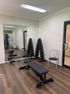 a gym with several rows of exercise equipment and a mirror at City CBD Retreat in Perth