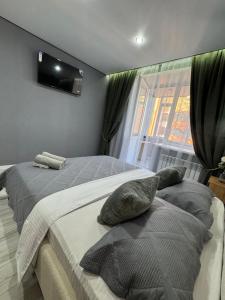 a bedroom with two beds and a television on the wall at Abay Apartments in Semey