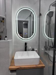 a bathroom with a white sink and a mirror at Abay Apartments in Semey