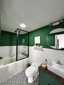 a green bathroom with a toilet and a sink at Loft ËNXË Boutique Habitación Green in Cuetzalán del Progreso