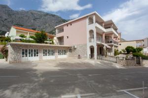 a house with a parking lot in front of a mountain at Ivan Apartment in Makarska