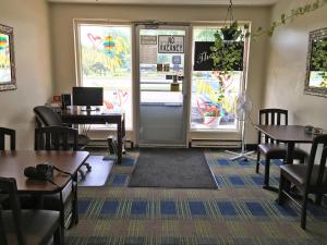 a waiting room with tables and chairs and a door at Westgate Inn in Portage La Prairie