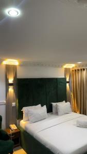 a bedroom with a large bed with a green headboard at Quarters Inn & Suites Ikeja in Ikeja