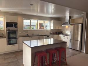 a kitchen with a large island with two red bar stools at Alpine Rose Retreat in Arrowtown