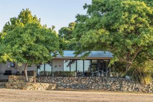 a house with a stone wall and two trees at Petra Olive 1 in Yallingup