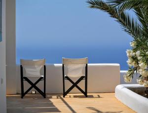 アナフィにあるVilla Aigliの海の壁の横に座る椅子2脚