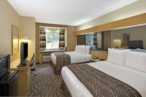 a hotel room with two beds and a flat screen tv at Microtel Inn by Wyndham University Place in Charlotte