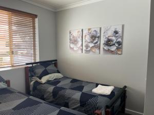 a bedroom with two beds and three pictures on the wall at Mandurah Central Estuary Soldiers cove Townhouse in Mandurah